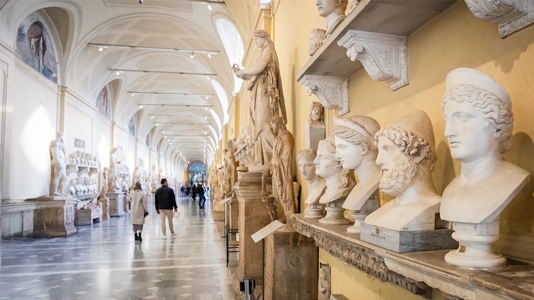 Visitors walking through Chiaramonti Museum hall with classical sculptures, Vatican Museums.