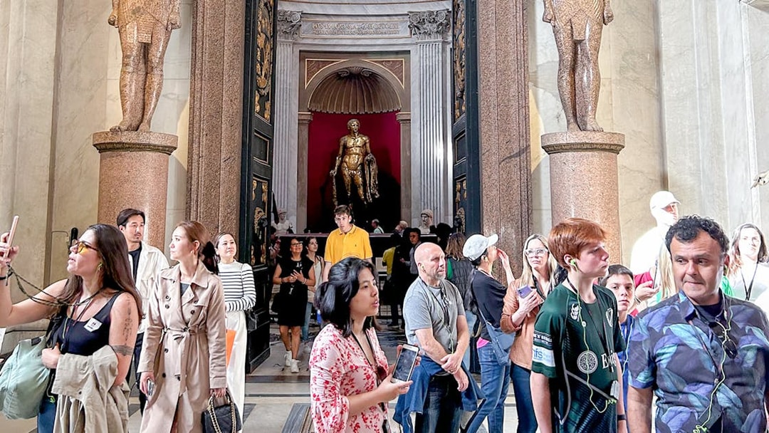 Visitors exploring the Vatican Museums entrance with statues and ornate doorway.