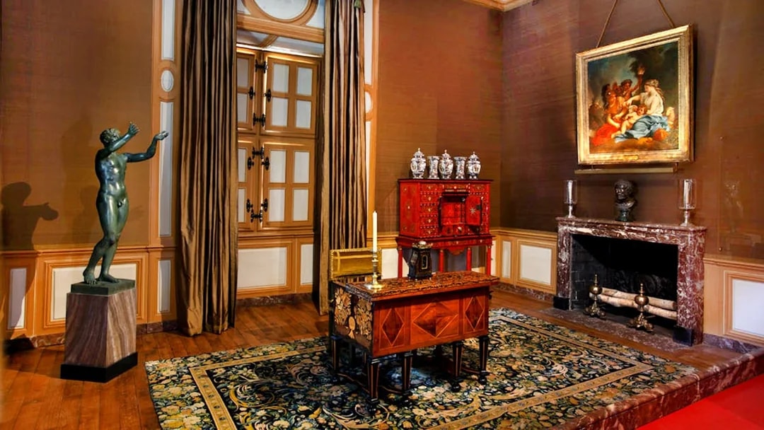 Interior of Vaux-le-Vicomte Castle with ornate desk, statue, and painting.