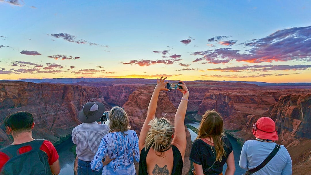 Tourists at Horseshoe Bend, Las Vegas, capturing sunset views over the canyon.