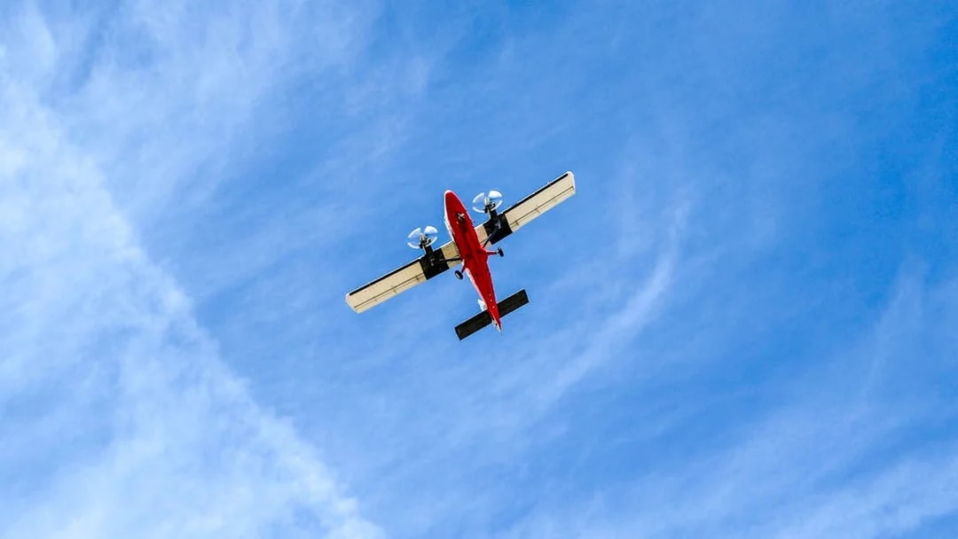 Red airplane flying overhead against a blue sky.