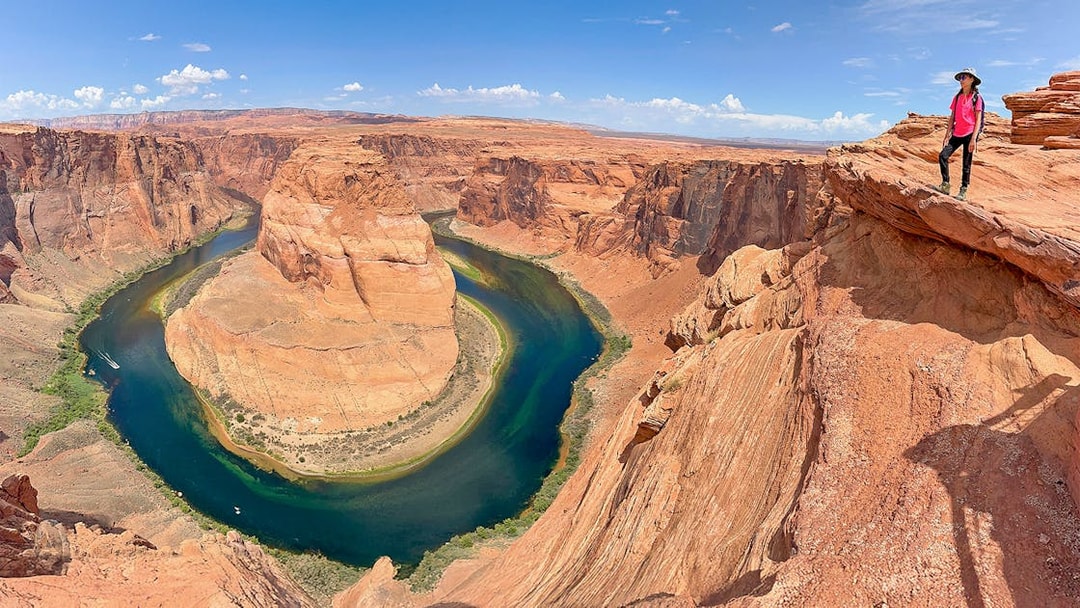 Horseshoe Bend view with a person standing on the edge, part of Lower Antelope Canyon tour from Las Vegas.
