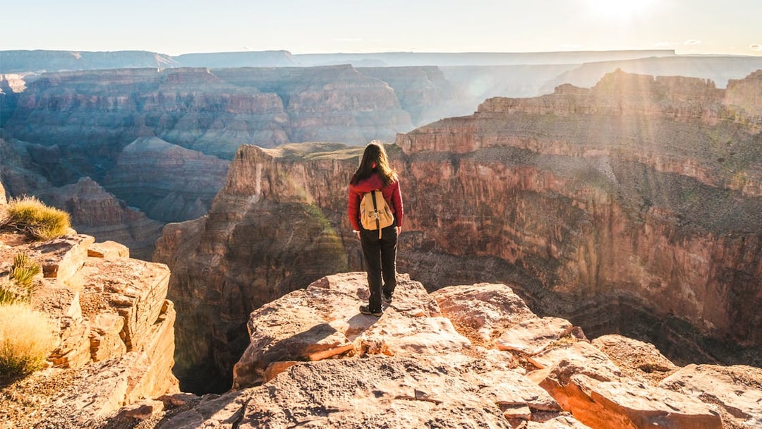 Person standing at the edge of the Grand Canyon, Arizona, overlooking vast canyon views.