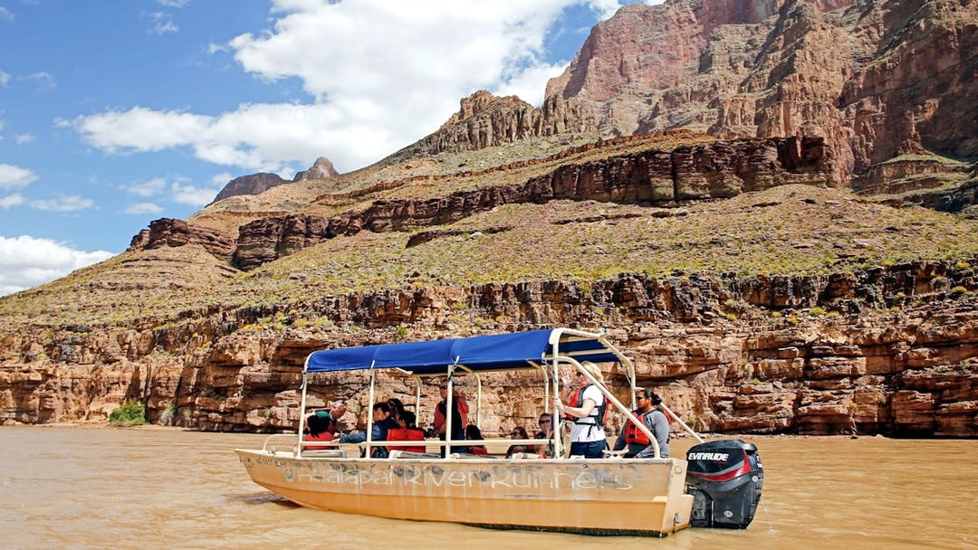 Boat ride on the Colorado River with tourists, Grand Canyon West Rim cliffs in background.