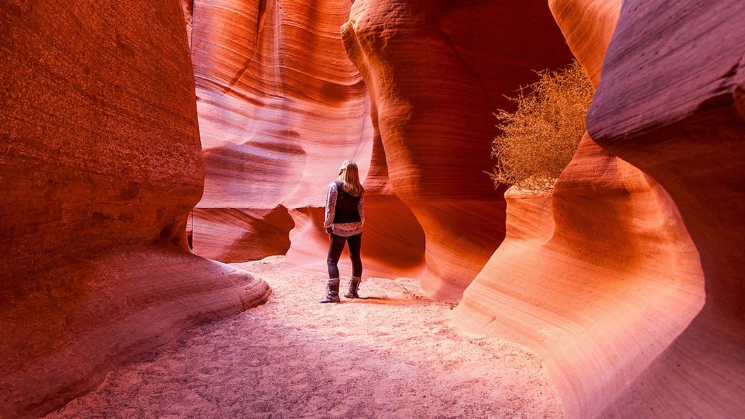 Visitor exploring the narrow sandstone walls of Antelope Canyon X, Arizona.