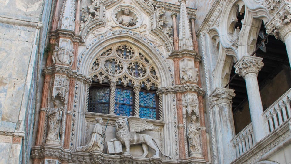 Facade of Doge’s Palace in Venice with ornate sculptures and stained glass windows.