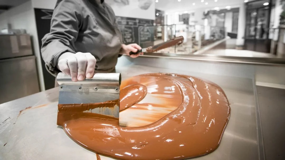 Chocolate being tempered on a metal table during a tasting tour in Venice.