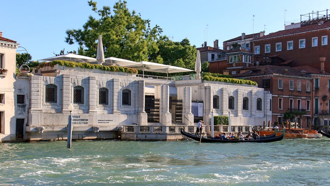 Peggy Guggenheim Collection museum along Venice's Grand Canal with gondola passing by.