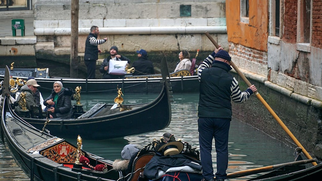 Gondola ride through Venice canal during Carnival with passengers and gondolier.