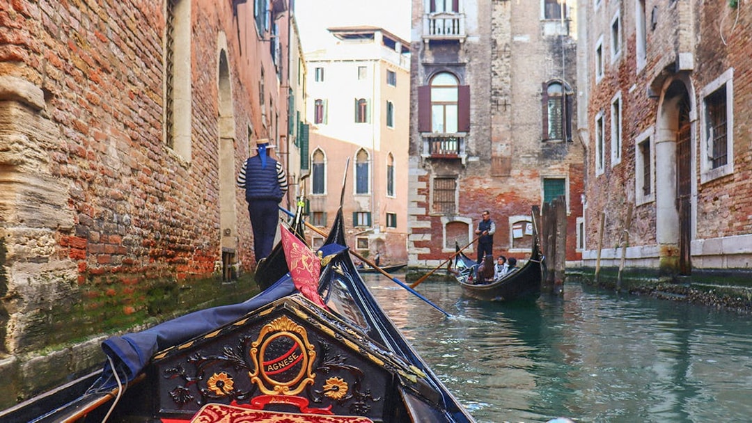 Gondola ride through narrow canal in Venice with tourists and gondolier.