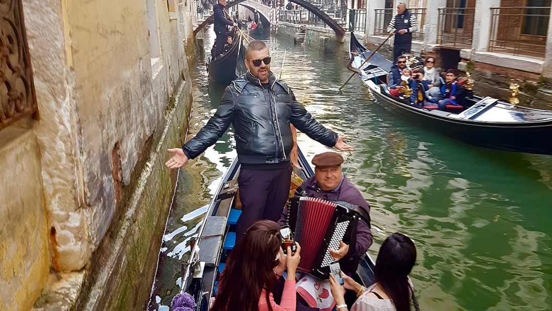 Gondola ride in Venice with musician playing accordion and singer performing.