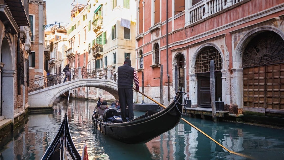 Gondola navigating a canal under a bridge in Venice during a guided walking tour.