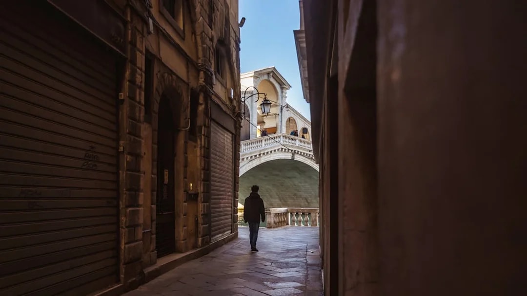 Walking through a narrow alley towards the Rialto Bridge in Venice.
