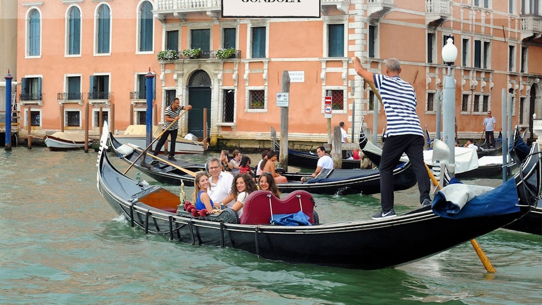 Gondola ride on a canal in Venice with tourists and gondoliers.