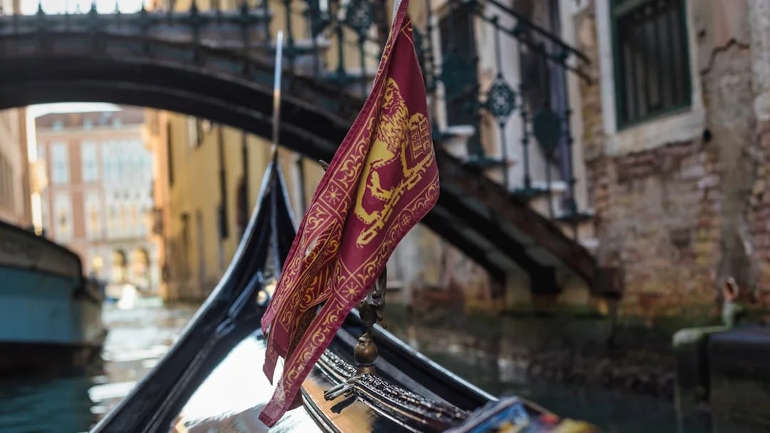 Gondola on a canal in Venice with a bridge in the background.