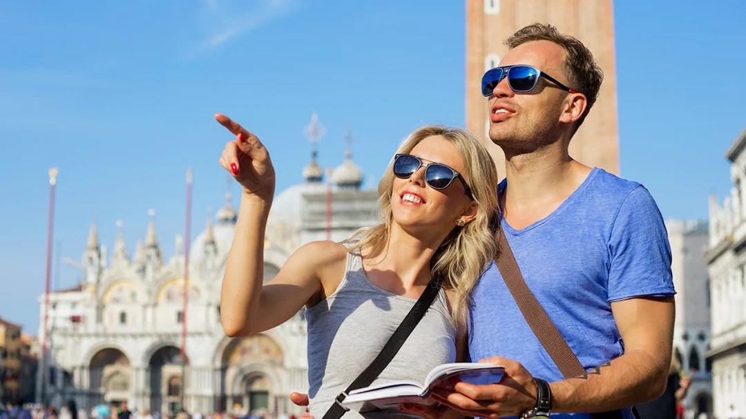 Tourists exploring St. Mark’s Basilica in Venice with a guidebook.