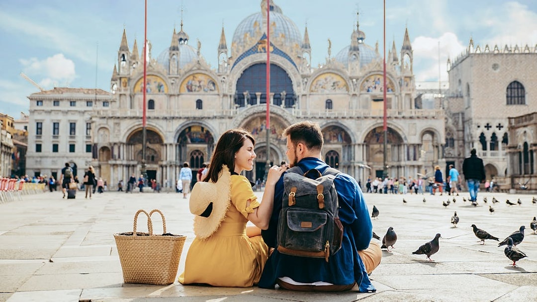 Tourists sitting outside St Mark's Basilica in Venice, Italy.