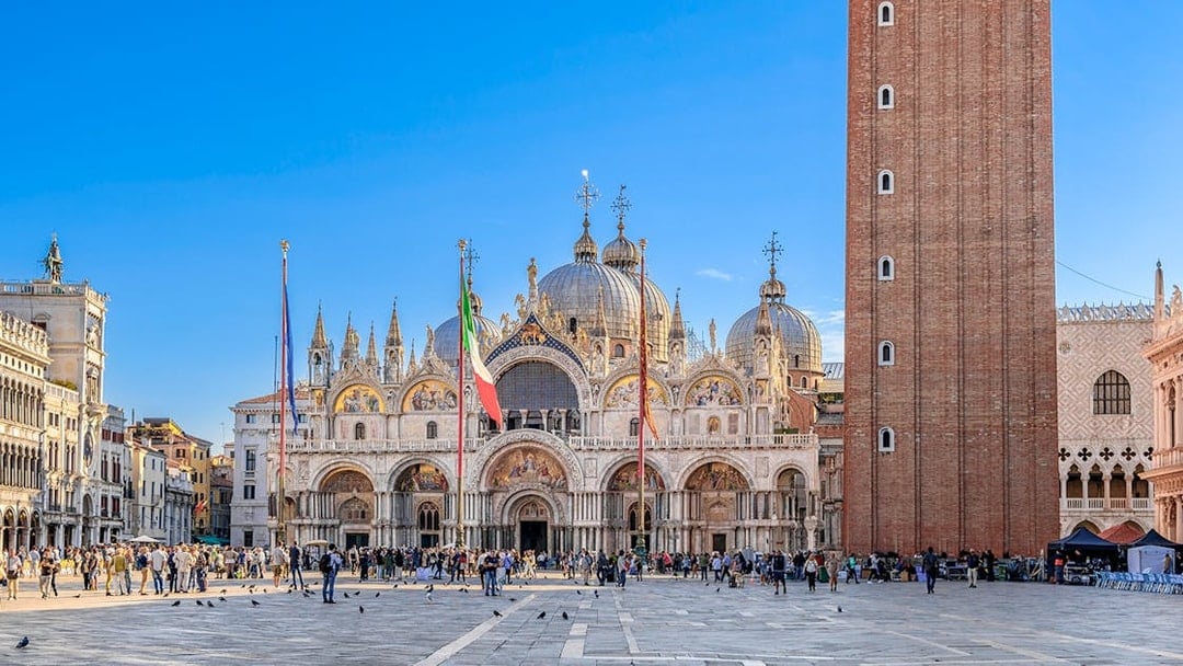 St. Mark's Basilica and Campanile in Venice with tourists in the square.