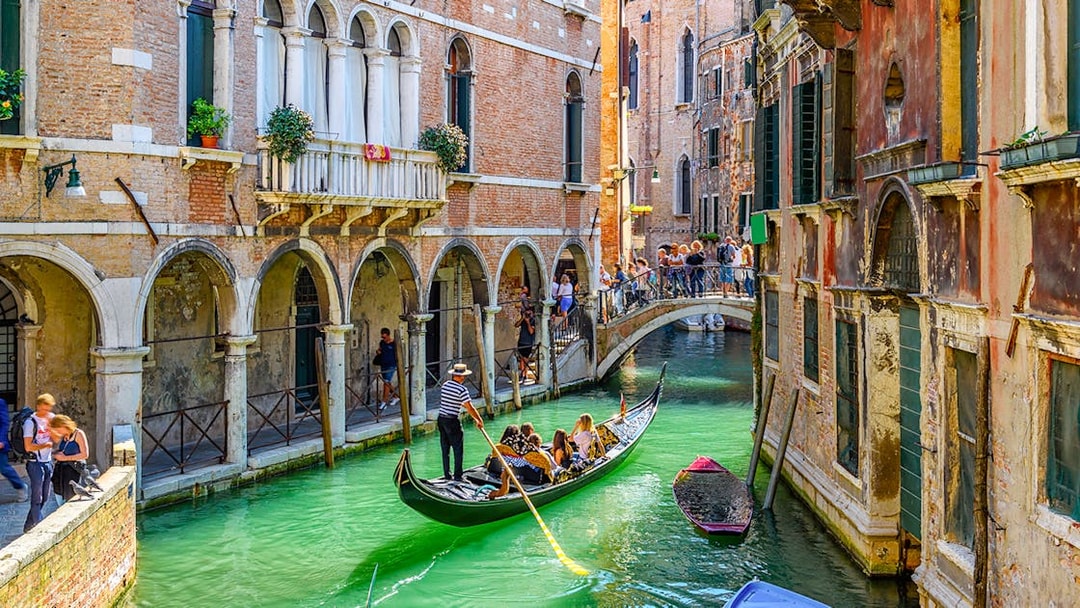 Gondola navigating a narrow canal under a bridge in Venice, Italy.