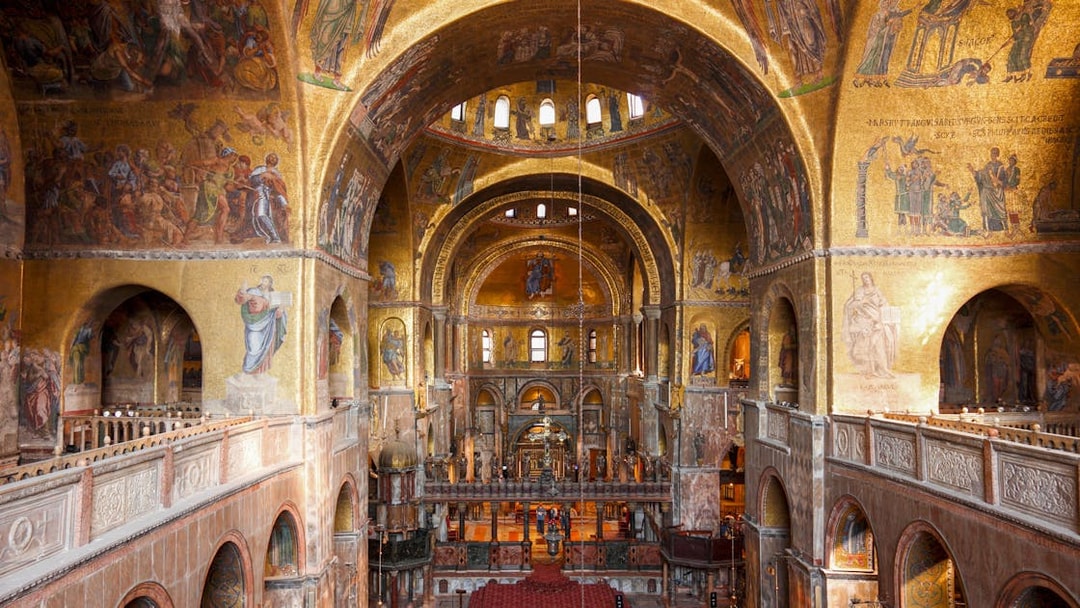 Interior view of St. Mark's Basilica with ornate golden mosaics and arches, Venice.