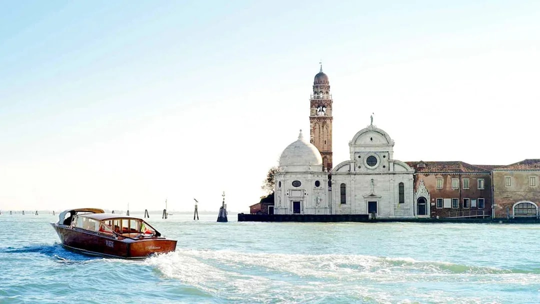 Private water taxi on Venetian lagoon near historic buildings, Venice transfer service.