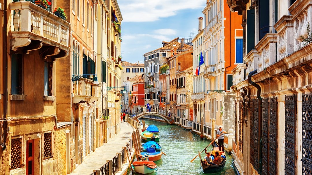 Venice canal with gondola and colorful buildings, part of a self-guided audio tour.