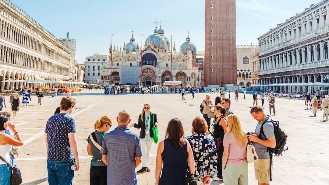 Tour group in Saint Mark's Square, Venice, with Basilica and Campanile in view.