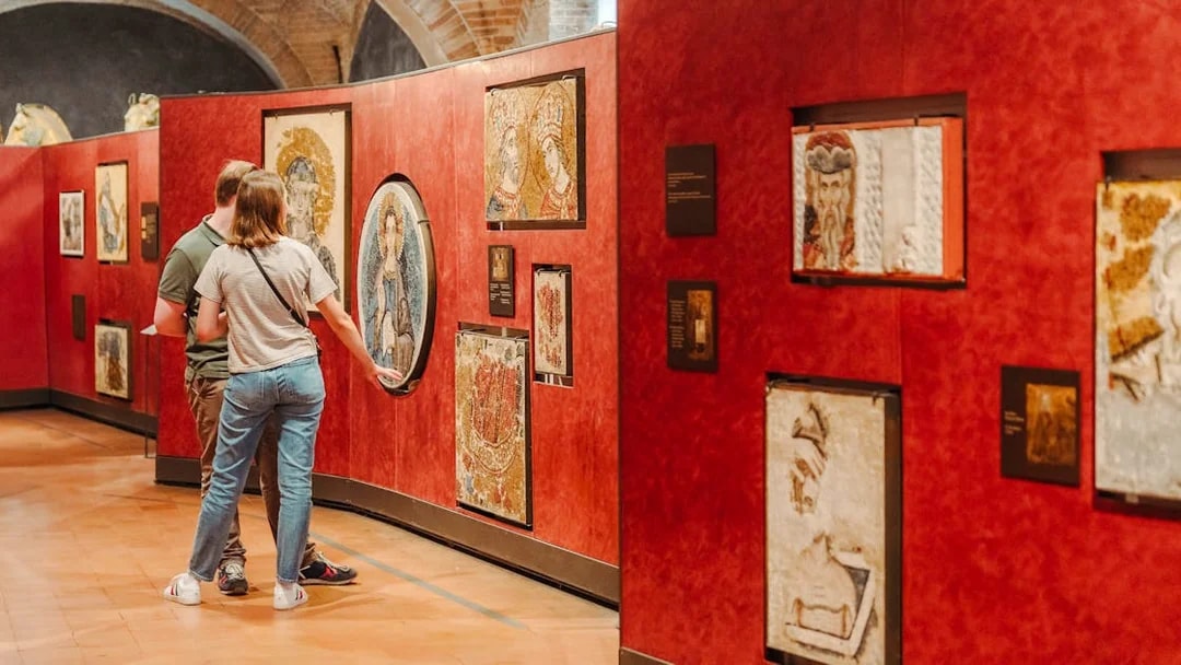 Visitors viewing mosaics at Doge's Palace exhibit during guided tour.