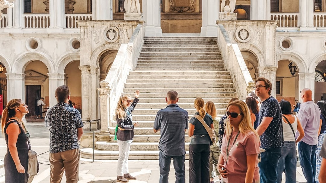 Tour group near Giants' Staircase at Doge's Palace, Venice, with guide explaining architecture.