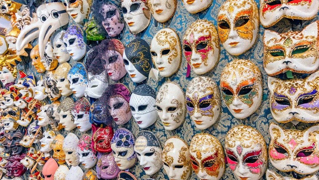 Venetian carnival masks displayed on a wall in Venice, Italy.