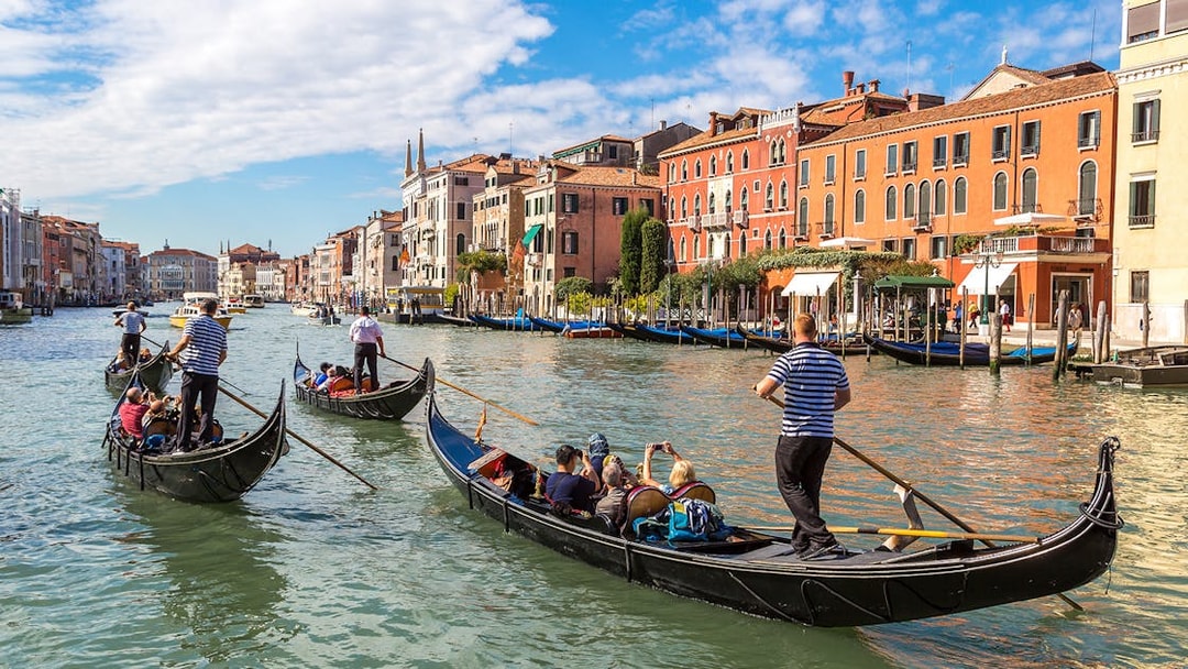 Gondolas navigating Canal Grande in Venice with historic buildings in the background.