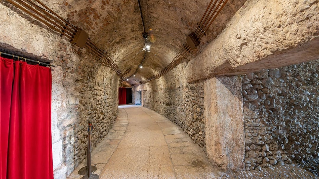 Interior hallway with stone walls and red curtains inside Verona Arena.