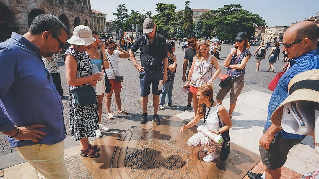 Tour guide explaining Verona Arena map to tourists outside the amphitheater.
