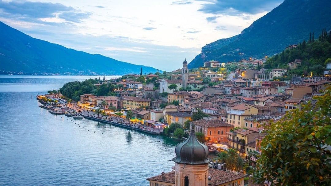 Verona and Lake Garda townscape with waterfront and mountains at dusk.