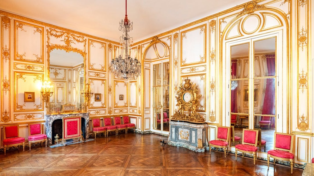 Versailles Palace King's Private Apartments with ornate gold decor and red chairs.
