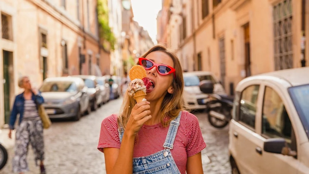 Person enjoying gelato on a cobblestone street in Rome.
