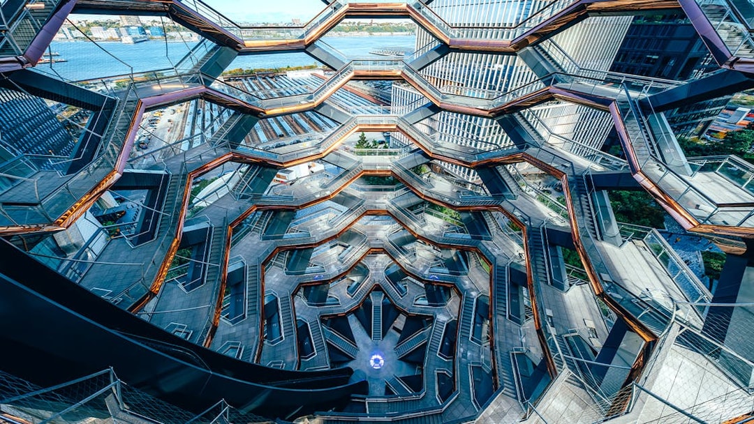 Vessel's intricate staircases and platforms in New York City with river view.