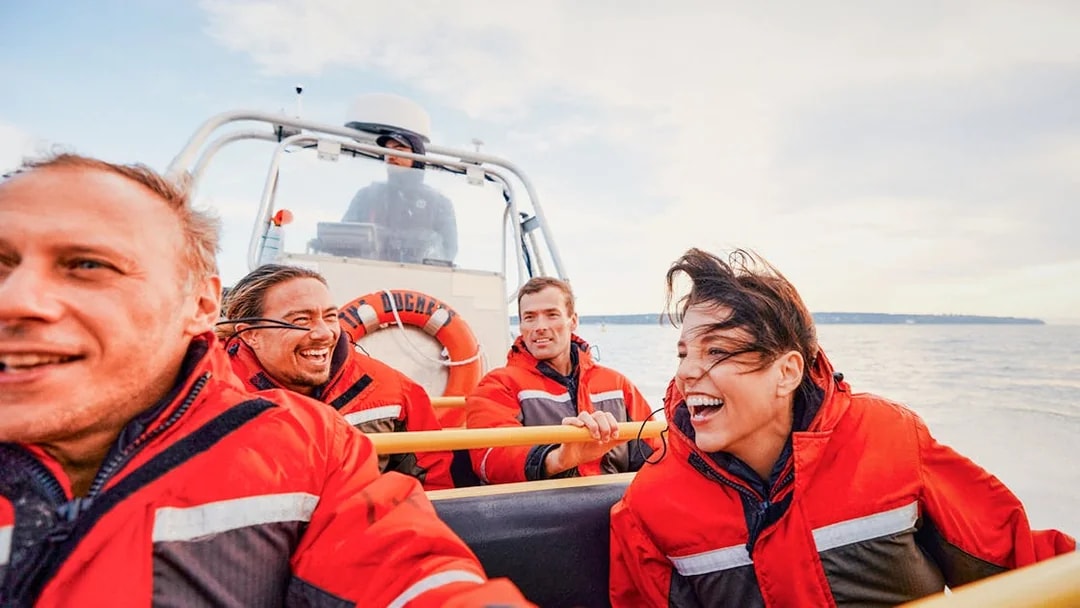 Four people in red jackets enjoying a Whale Watching Tour on a boat.
