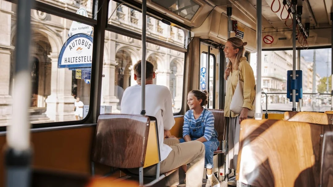 Tourists enjoying a tram ride in Vienna, with views of historic architecture outside.