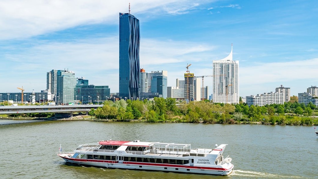 Danube cruise boat on river with Vienna skyline in background.