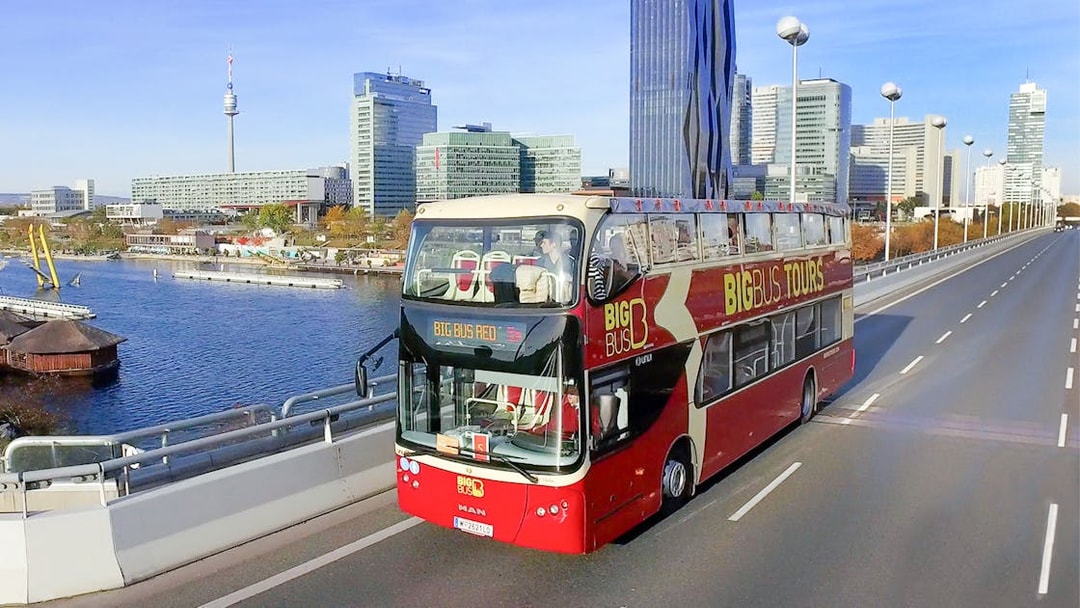 Big Bus tour in Vienna with city skyline and Danube River in the background.