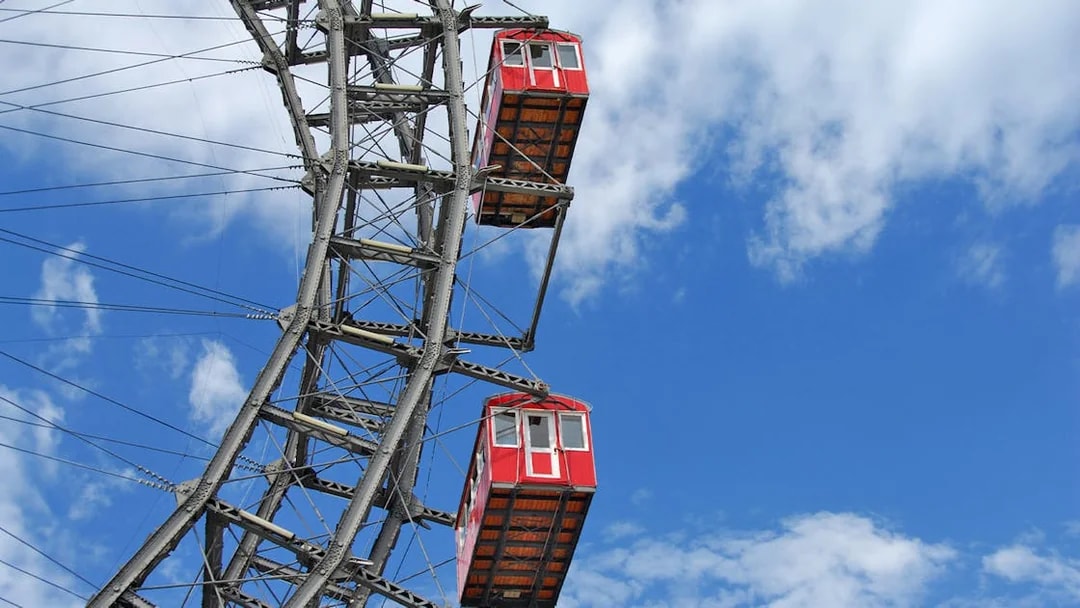 Red cabins on the Vienna Ferris Wheel against a blue sky.