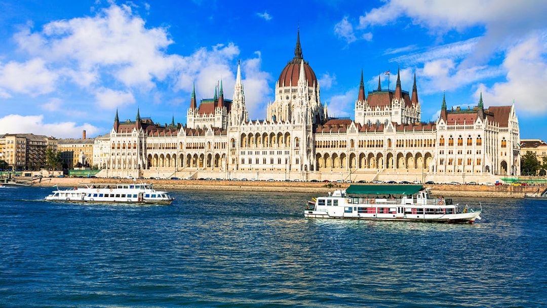 Danube River cruise boats passing the Hungarian Parliament Building in Budapest.