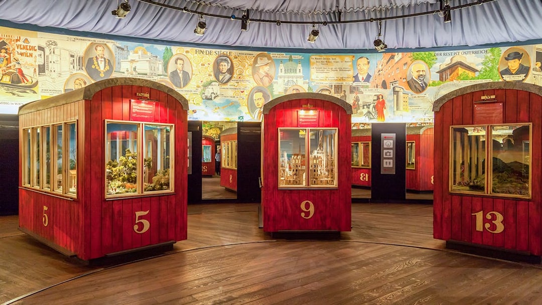 Red exhibition pods at The Wheel of History ‘Panorama’ with historical murals in the background.