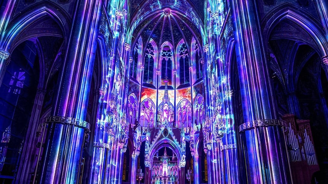 Vibrant light display inside Votivkirche, Vienna, showcasing colorful illuminated arches.