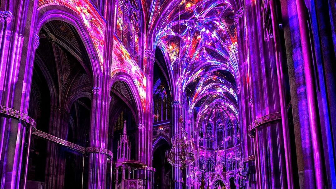 Vibrant light display inside Votivkirche, Vienna, showcasing colorful illuminated arches.