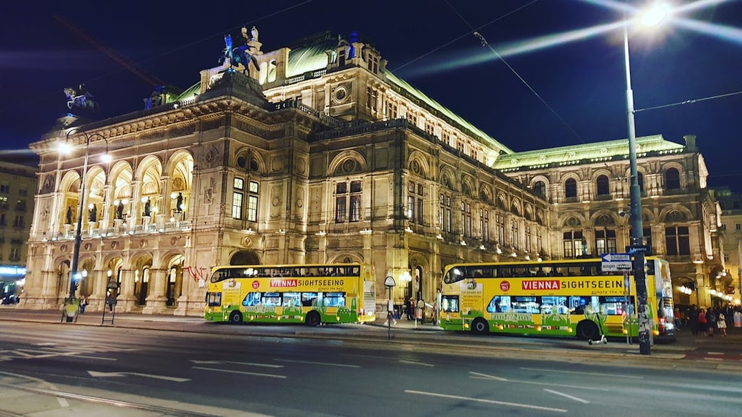 Vienna State Opera at night with sightseeing buses in front.