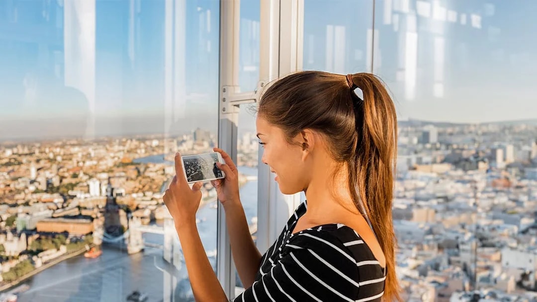 Tourist capturing panoramic views of London from the Shard.