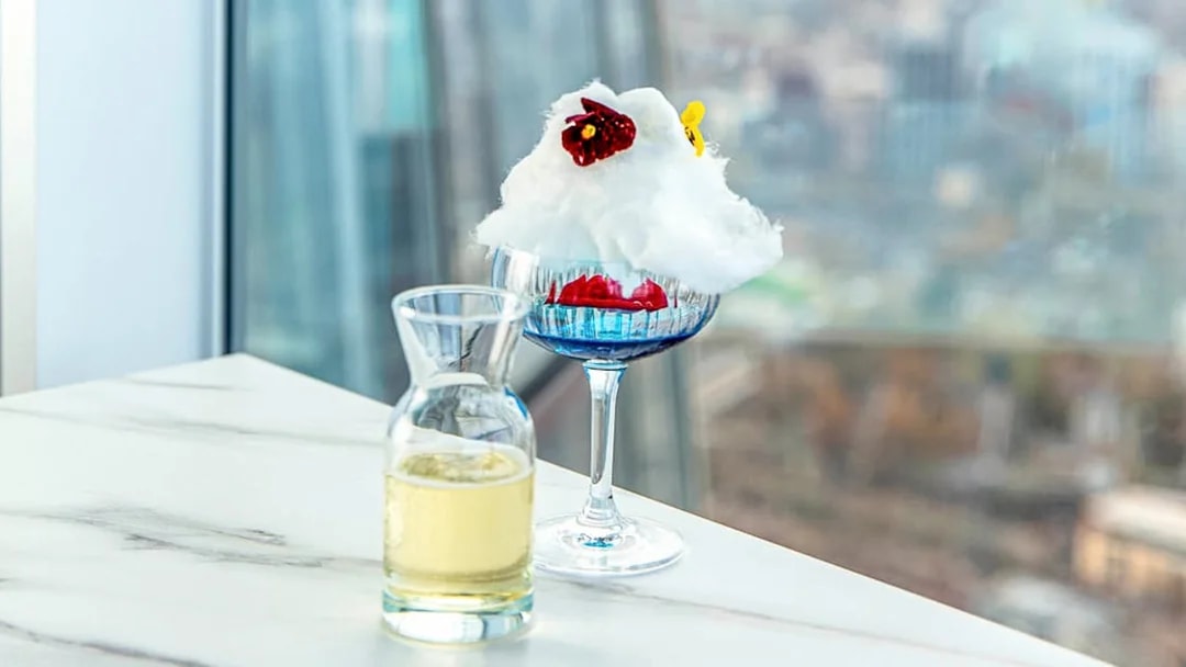 Champagne and dessert on a table with a view from The Shard in London.