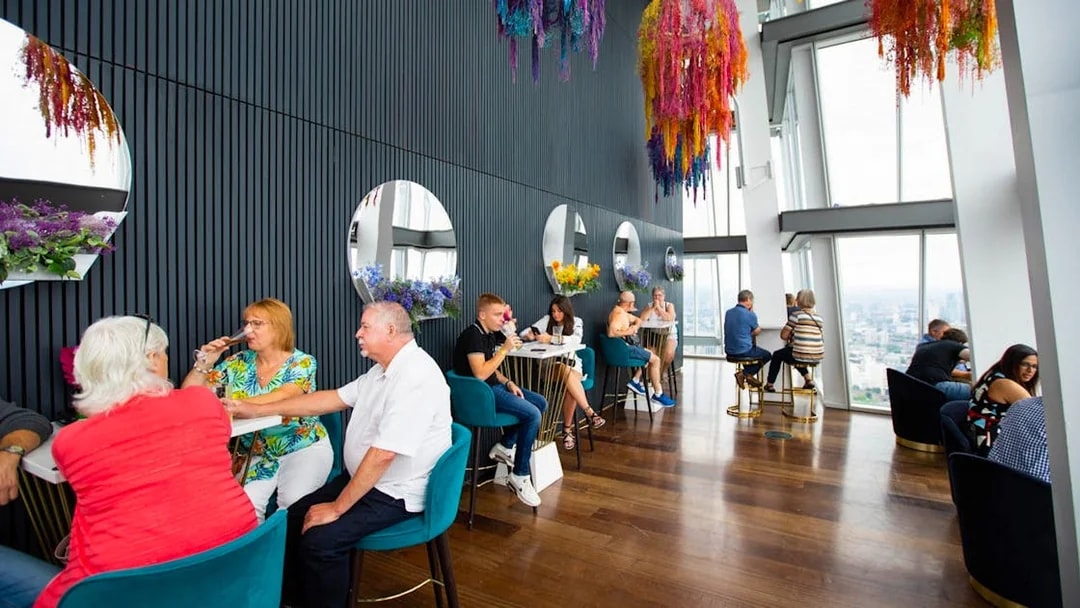 People enjoying drinks at a table with city views from the top of the Shard in London.
